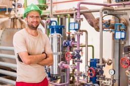 industry-worker-posing-inside-factory-with-bars-pipes-around.jpg