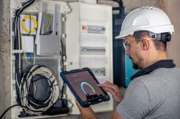 man-electrical-technician-working-switchboard-with-fuses-uses-tablet.jpg